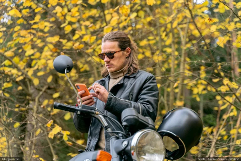 Ein Biker mit seinem Handy, auf dem er nach der App Meet5 Biker treffen sucht.